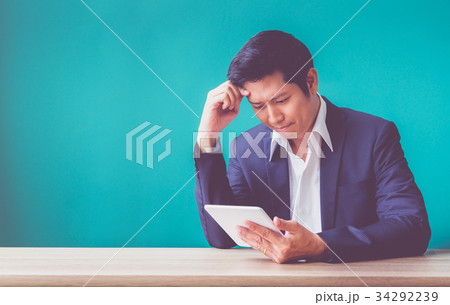 Businessman sitting at wood table looking down 34292239