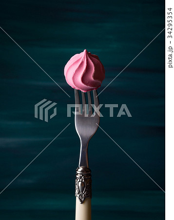Pink meringue on fork on dark green 34295354