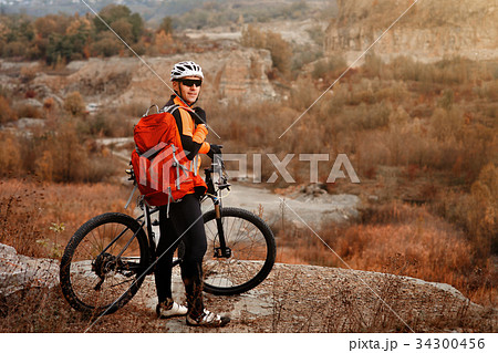 back view of a man with a bicycle and red backpack back view of a man with a bicycle and red backpack 34300456