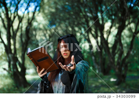 Young witch in dark forest 34303099
