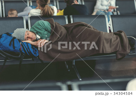 Tired guy is sleeping in airport lounge Tired guy is sleeping in airport lounge 34304584