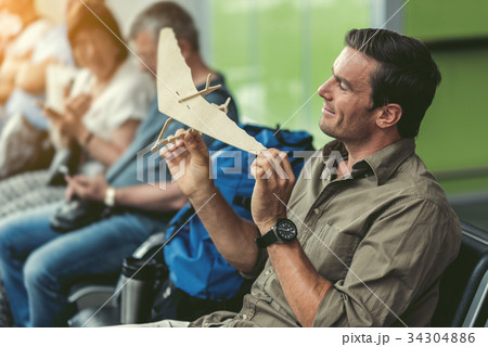 Cheerful man is resting on bench and holding toy Cheerful man is resting on bench and holding toy 34304886