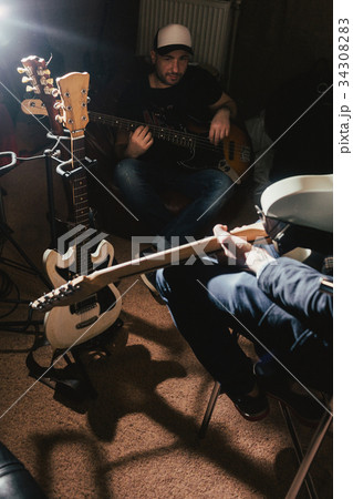 Guitarists rehearsing in dark music studio Guitarists rehearsing in dark music studio 34308283