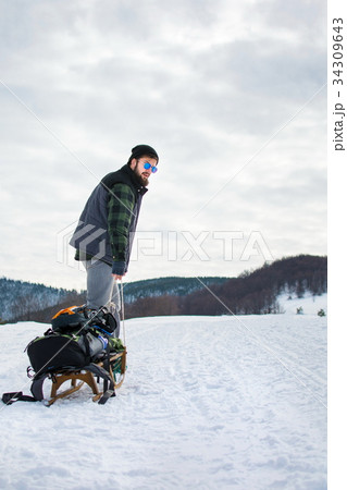 Man puling sleights up snowy mountain 34309643