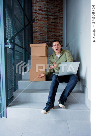 Handsome man with moving boxes and laptop  34309754