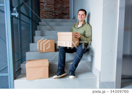 Handsome man with moving boxes sitting on stairs 34309760