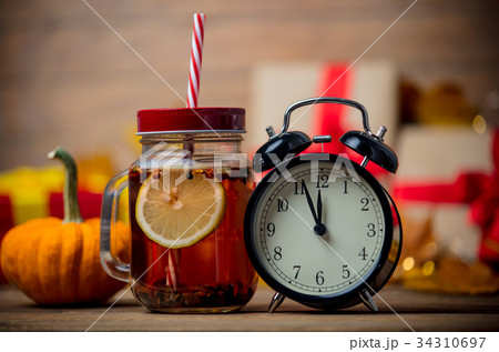 Tea and alarm clock next to pumpkin Tea and alarm clock next to pumpkin 34310697