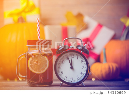 Tea and alarm clock next to pumpkin  34310699