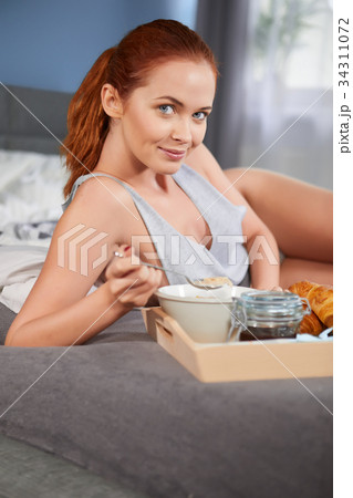 Beautiful happy redhead woman having breakfast in bed Beautiful happy redhead woman having breakfast in bed 34311072