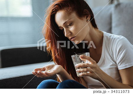 Cheerless attractive woman holding a glass of Cheerless attractive woman holding a glass of 34311073