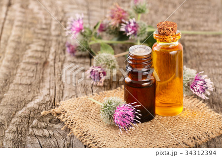 burdock oil in glass bottle and burdock flowers on burdock oil in glass bottle and burdock flowers on 34312394