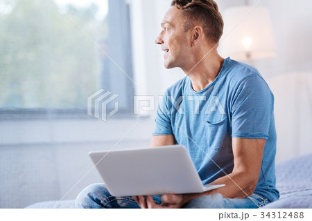 Cheerful man holding laptop and looking into the 34312488