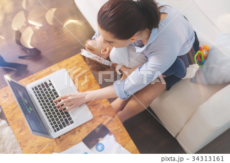 Attentive brunette looking at screen of her laptop Attentive brunette looking at screen of her laptop 34313161