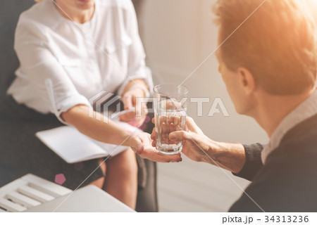Nice professional psychologist giving a glass of Nice professional psychologist giving a glass of 34313236