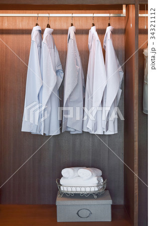 row of white shirts hanging in wooden wardrobe row of white shirts hanging in wooden wardrobe 34321112