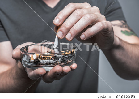 Male arms extinguishing cigarette butt Male arms extinguishing cigarette butt 34335598