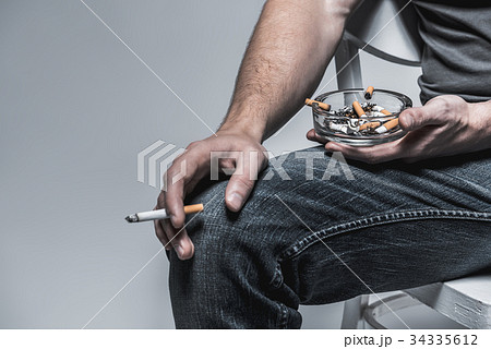Man holding ashtray with stubs near legs 34335612