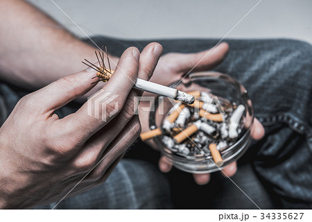 Male hand keeping cigar with needles on filter Male hand keeping cigar with needles on filter 34335627