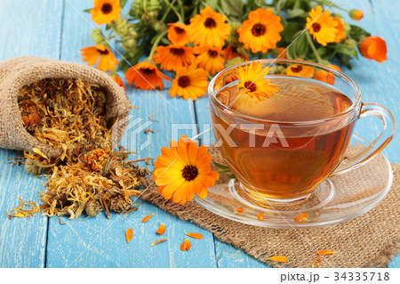 Calendula tea with fresh and dried flowers on blue 34335718
