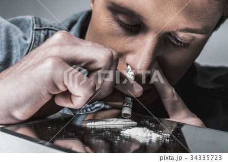 Male junkie inhaling while coke though paper 34335723