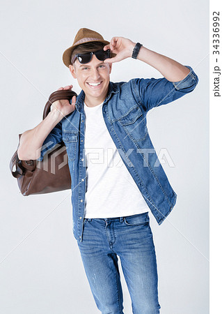 man in hat and sunglasses carrying leather bag on 34336992