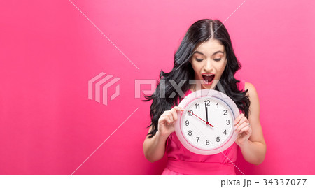 Woman holding clock showing nearly 12 34337077