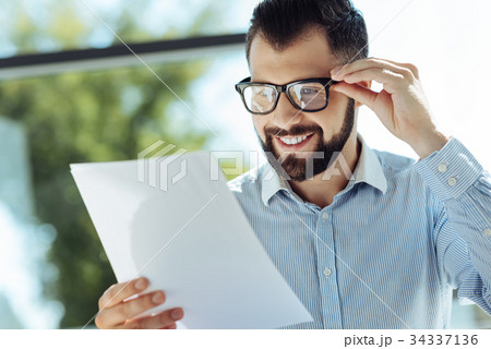 Bearded young man looking at documents and smiling 34337136