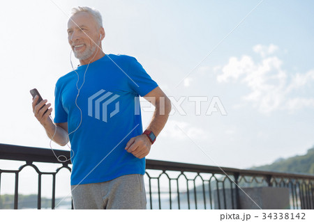 Upbeat elderly man listening to music while 34338142