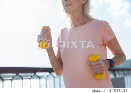 Close up of senior lady with two yellow dumbbells Close up of senior lady with two yellow dumbbells 34338155