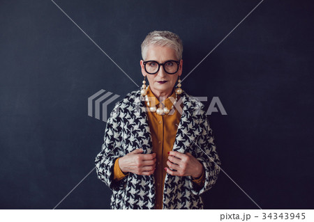 Stylish old woman in glasses standing on a black Stylish old woman in glasses standing on a black 34343945