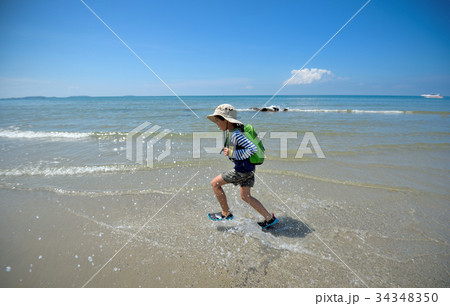 The boy runs to the sea at the beach cheerfully cheerful. On a c 34348350