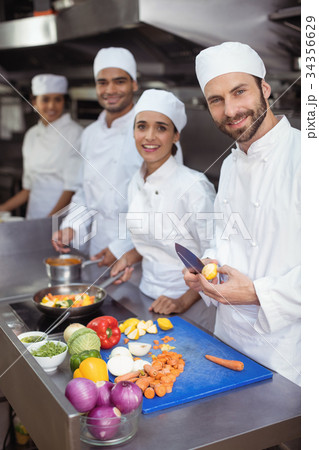 Chefs chopping vegetables on chopping board in the commercial kitchen 34356629