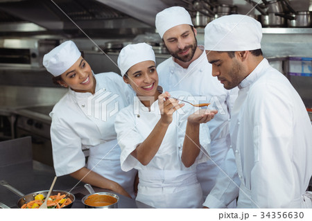Chef tasting food to colleague in kitchen 34356630