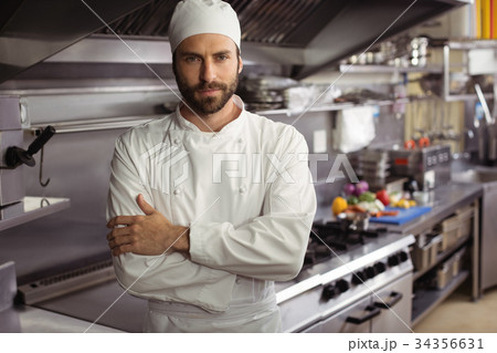Portrait of confident chef standing with arms crossed in commercial kitchen 34356631