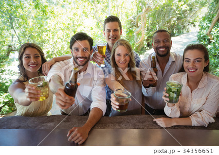 Portrait of smiling friends showing alcohol at counter Portrait of smiling friends showing alcohol at counter 34356651