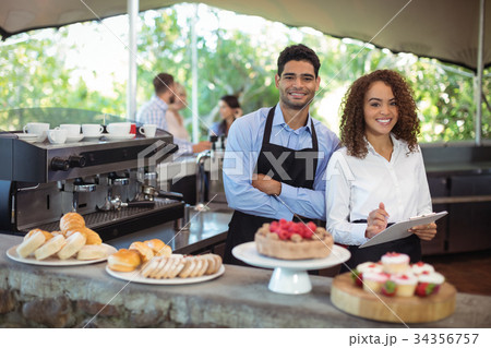 Waiter and waitress standing with clipboard at counter in restaurant 34356757