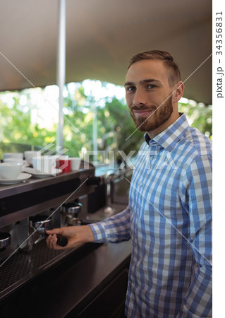 Waiter using tamper to press ground coffee into a portafilter Waiter using tamper to press ground coffee into a portafilter 34356831