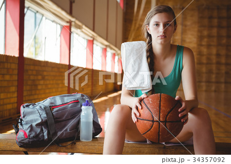 Portrait of female basketball player sitting on bench Portrait of female basketball player sitting on bench 34357092