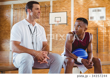 Smiling coach guiding basketball player Smiling coach guiding basketball player 34357244
