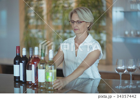 Businesswoman arranging winebottles on table Businesswoman arranging winebottles on table 34357442
