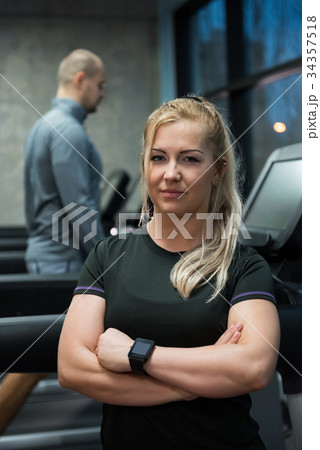 Portrait of woman standing with man exercising on treadmill Portrait of woman standing with man exercising on treadmill 34357518