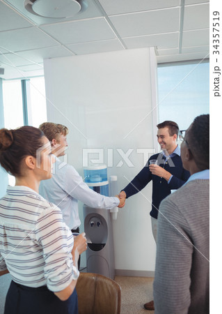 Happy business colleagues shaking hands at office Happy business colleagues shaking hands at office 34357519
