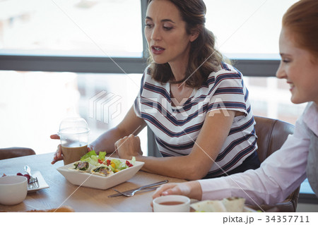 Female business colleagues having breakfast at office cafeteria Female business colleagues having breakfast at office cafeteria 34357711