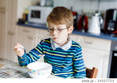 Happy little blond kid boy eating cereals for 34357723