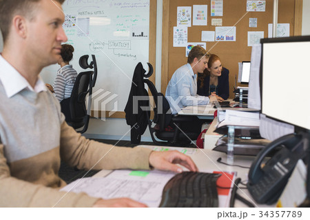 Young coworkers discussing while working in office Young coworkers discussing while working in office 34357789