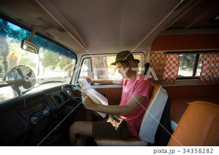 Side view of man reading map in camper van 34358282
