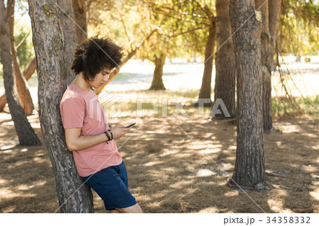 Side view of man using mobile phone at forest 34358332