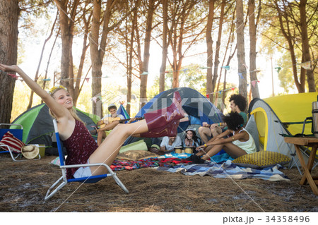 Cheerful woman sitting on chair at campsite 34358496