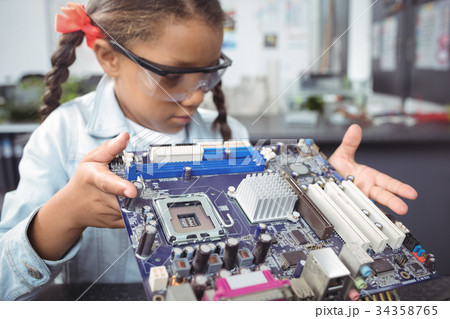 Elementary schoolgirl examining circuit board at electronics lab Elementary schoolgirl examining circuit board at electronics lab 34358765