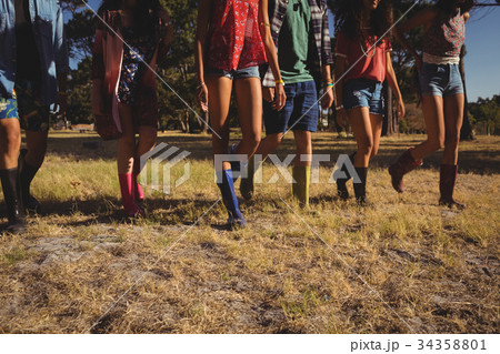Low section of friends walking on field 34358801